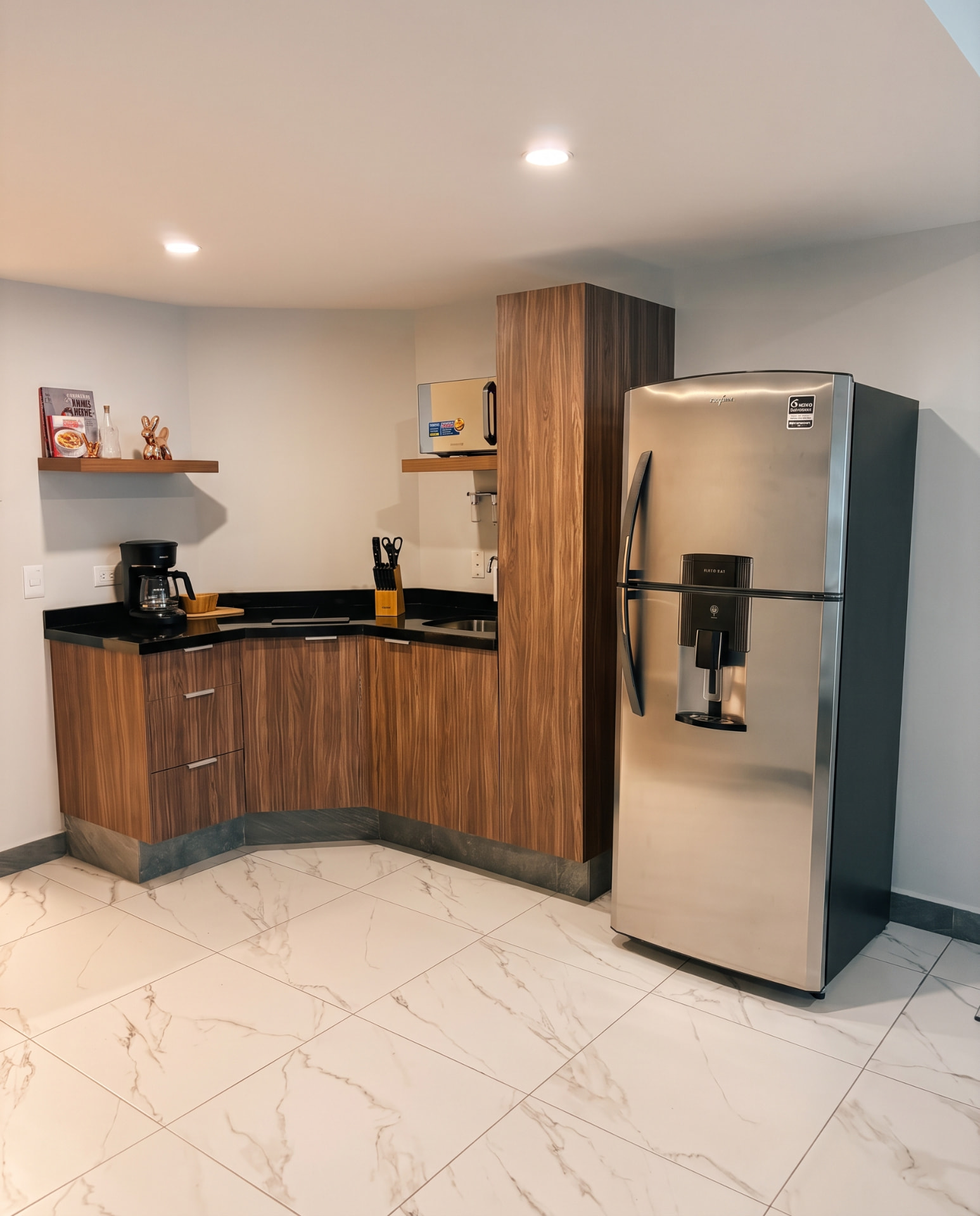 Cocina con gabinetes de madera, cubierta negra y refrigerador