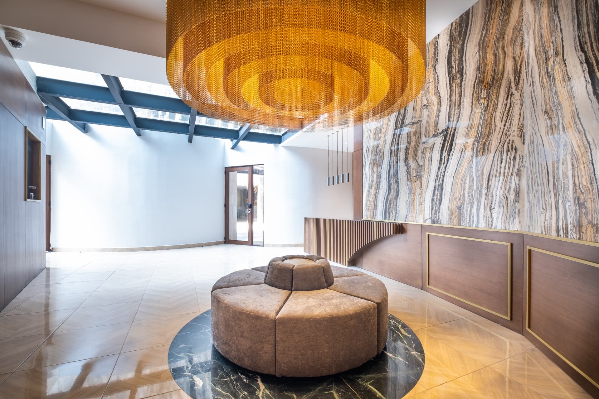 Lobby con lámpara dorada, asiento circular y muro de piedra natural